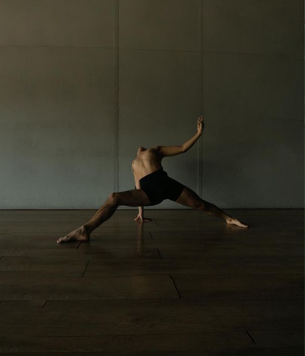 Man performing a controlled strength exercise in a dark, minimalist setting.